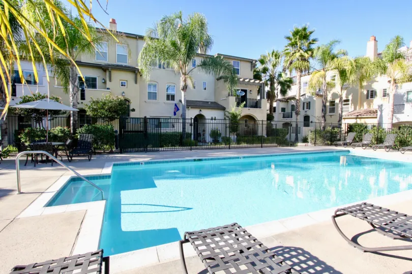 A sunny day in San Moritz has villa's with swimming pool, chairs and trees