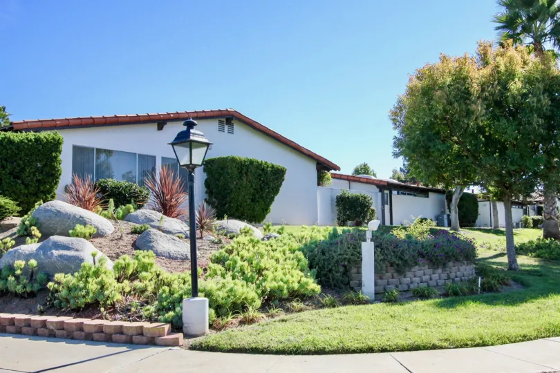 A one story home with landscaping and a lamp post in Seven Oaks Haciendas