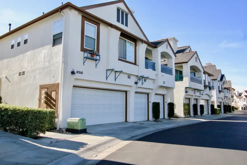 Several two story houses with sidewalks on a clear day in Sitella