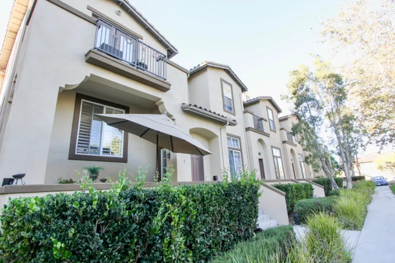 In Sycamore walk, A villa has umbrella in front the house with bushes and grasses