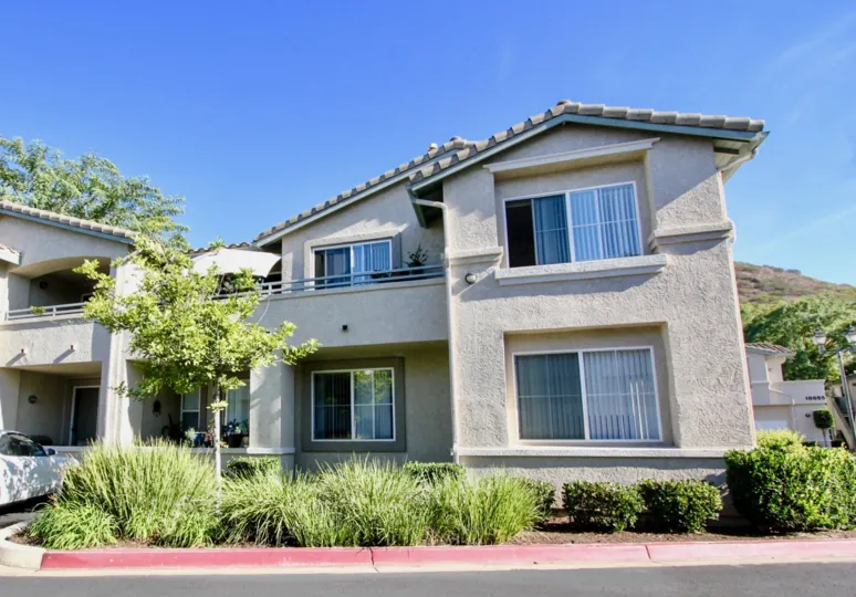 A sunny day in Vista Del Lago has villa's with trees and bushes