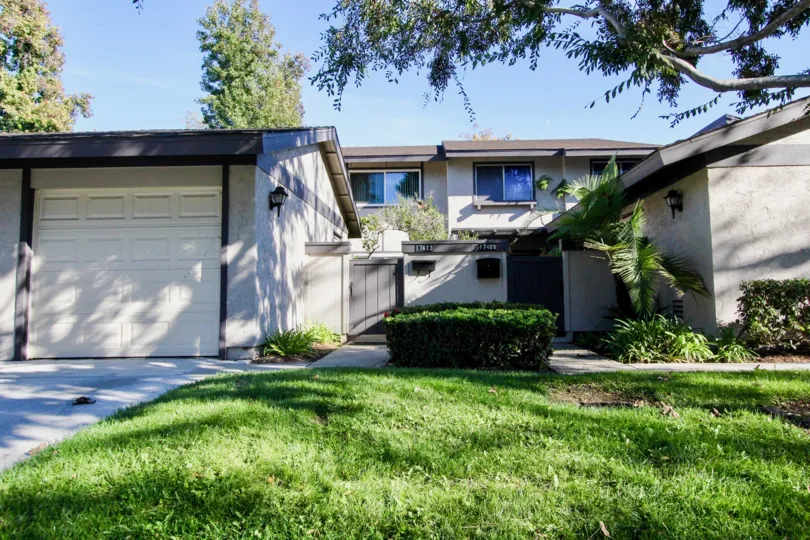 The villa's in the Westwood Townhomes has grass and bushes in front the home aside of the pathway