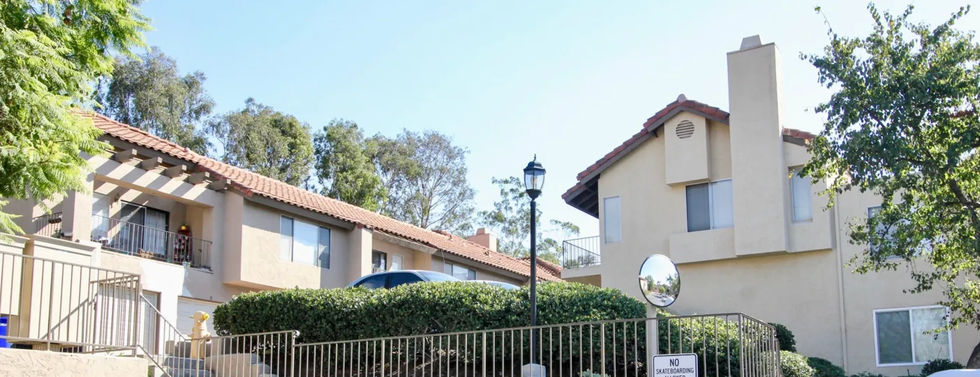 front view with bushes and fence in front and classic buildings in the back with lamp post