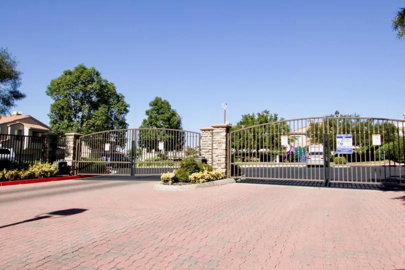 Double wide gated car entrances with red brick paved pads and parking stalls at Campana