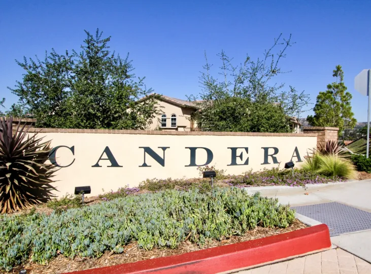 The front entrance sign of the Candera subdivision with landscaping under a clear blue sky.