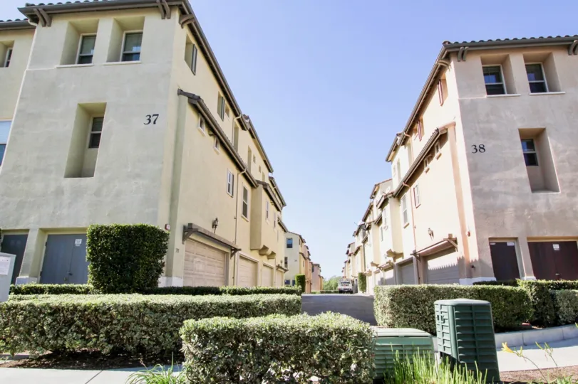 A view of the driveway between two units at the Coronado Ranch apartments in San Marcos showing ground floor garages and unit windows.