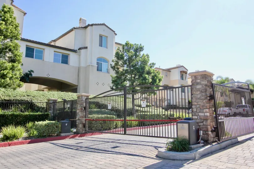 Brick paved road with double gated entrances lined with low hedges and a center median at Coronado Ranch