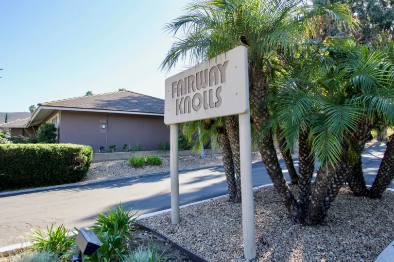 At the entrance, A board is placed in the pebbles with plants of Fairway Knolls