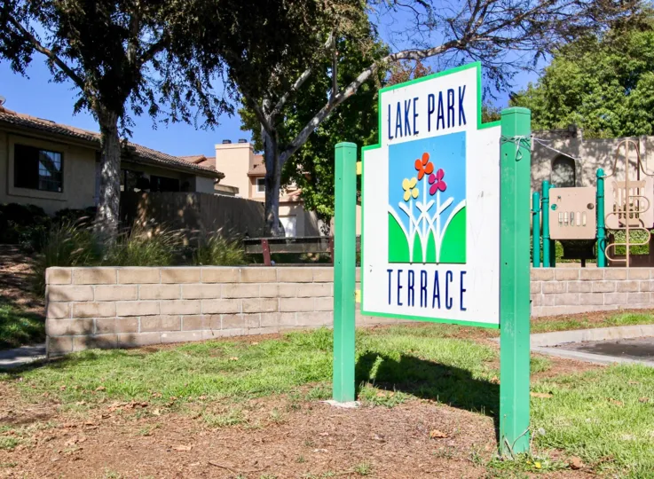 Colorful community entrance sign with brick stubwall and children's playground in the back in San Marcos