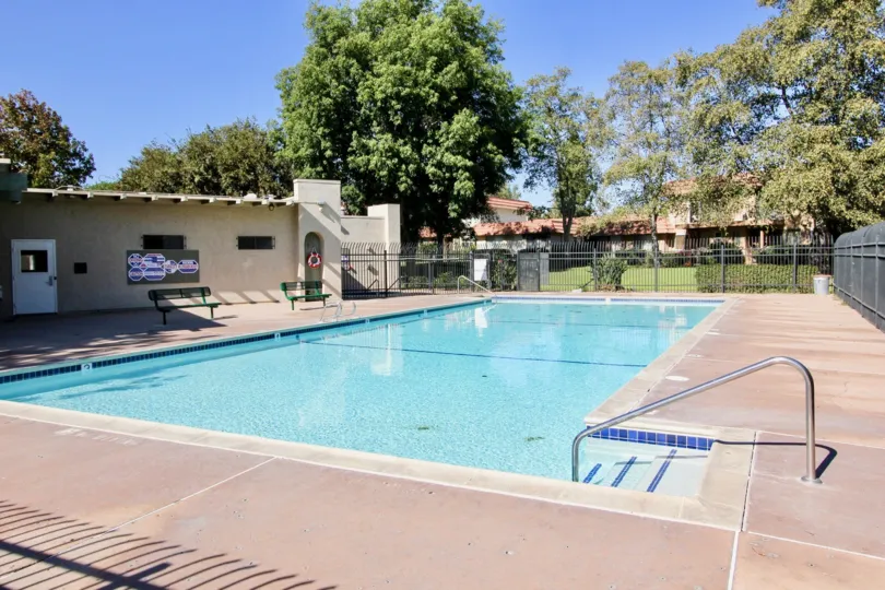 Private community swimming pool with iron railing fences surrounded by mature trees and pool house at Lake Park Terrace