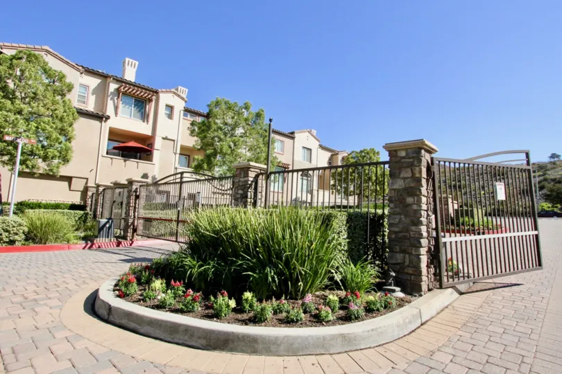 Brick paved entry road with gated access and a median with will grasses and flowers in San Marcos