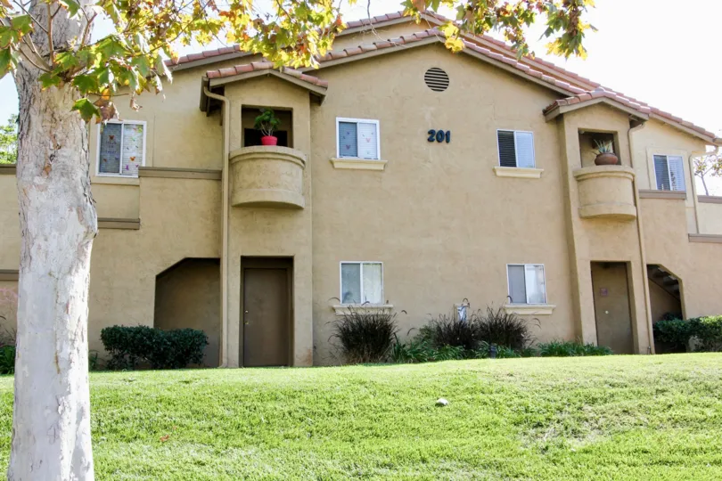 Two story residence with a potted plant on a balcony in Mission Park at San Marcos CA
