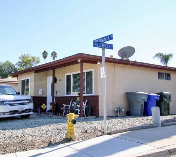 Car is parking and Has street board located two places with dusbin's
