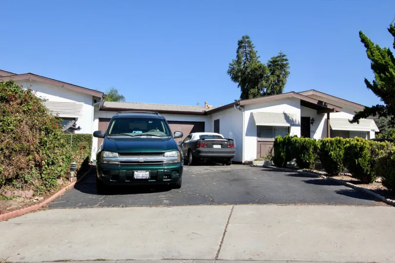 Two vehicles are parked in a wide driveway at a home in San Marcos Manor