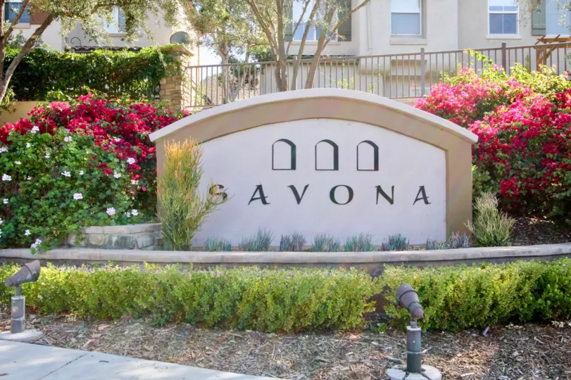 Lights point toward the community sign in front of a fence at the Savona residential building