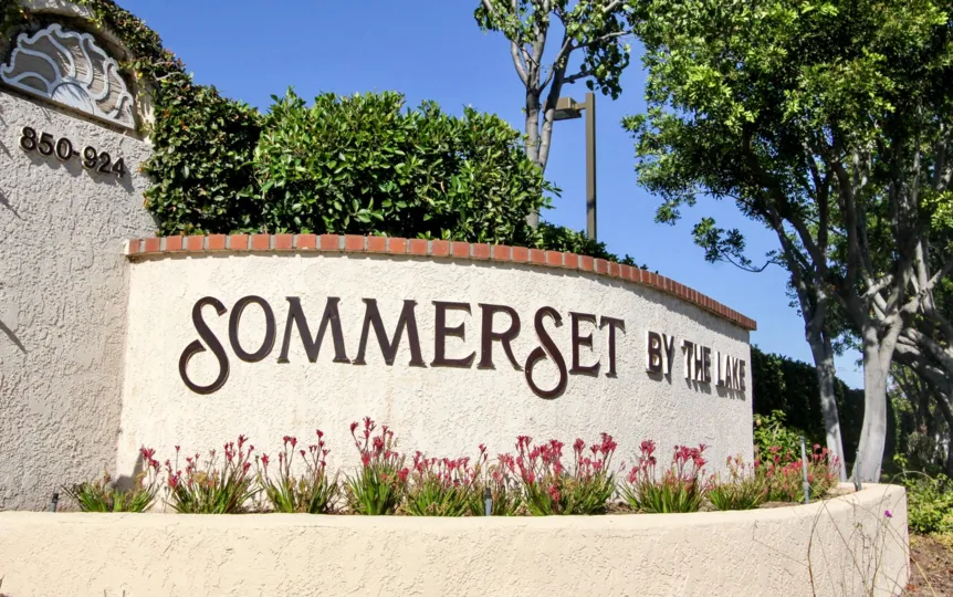 Black letters on a cement wall with red bricks at Sommerset By The Lake in San Marco CA