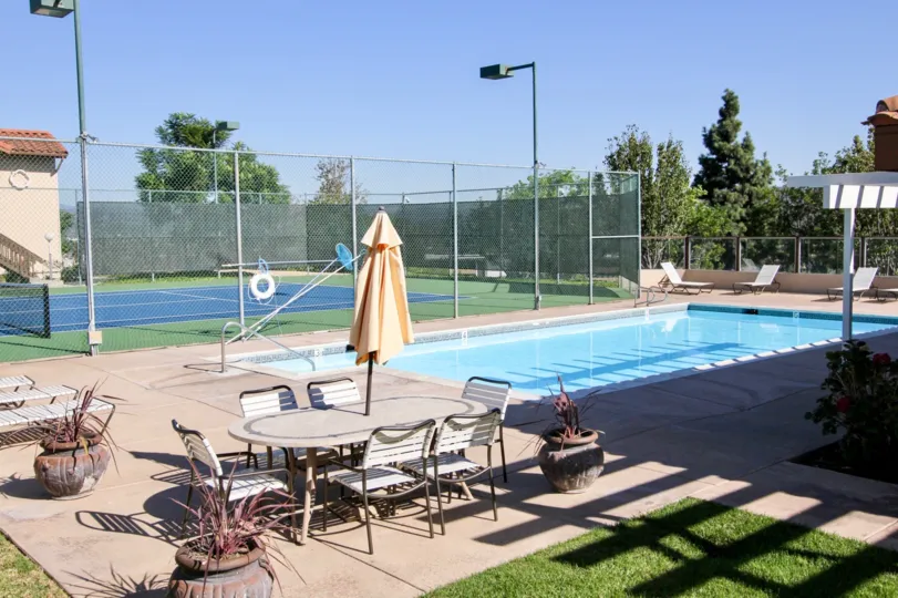 A patio table and chairs sit near the pool at Sommerset By The Lake