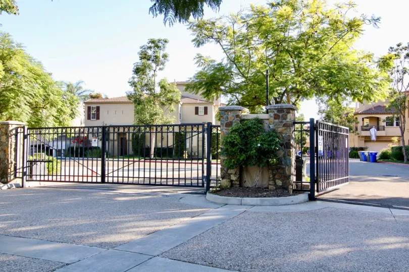 Double gated road entrance paved in exposed aggregate with planted median in San Marcos
