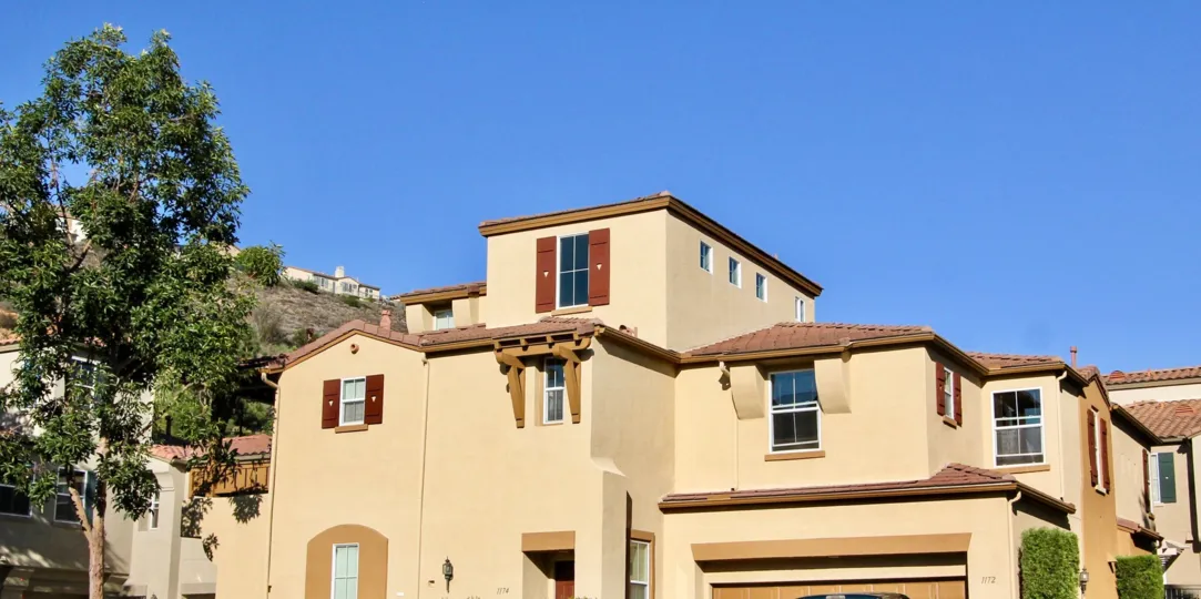 A tan Spanish style house sits near a steep hill in Springfield condos