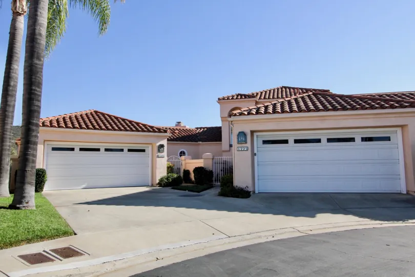 Two white garage doors on pink units near palms inside The Colony at San Marcos CA