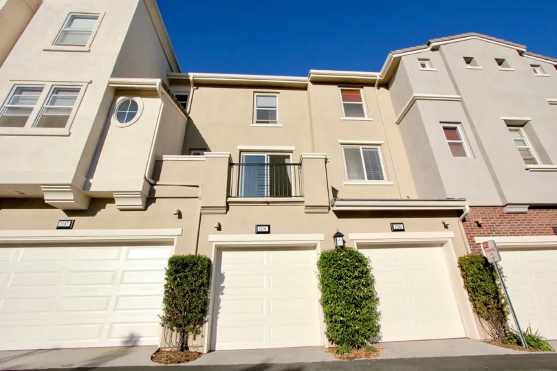 Single and double car garage homes with pastel colored stucco exteriors and small private balcony in Village Square