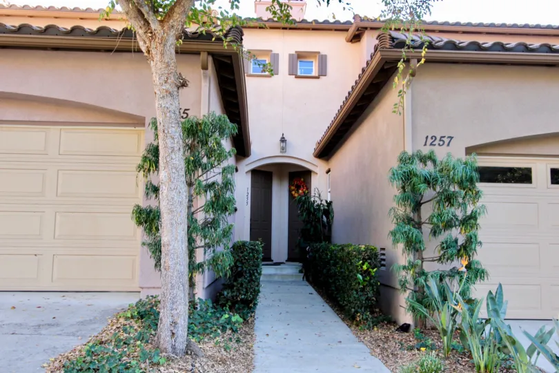 view of a housing with two garages visible on both sides and main door in the middle