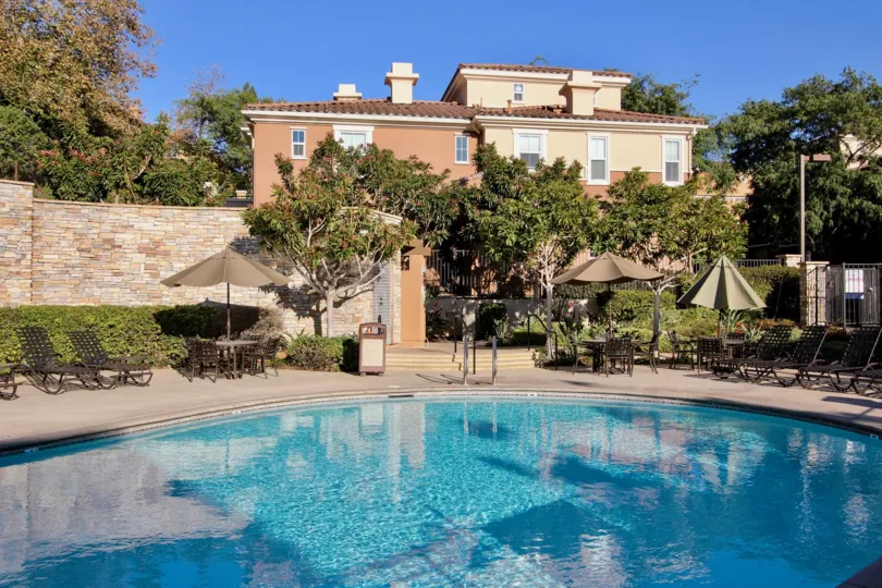 Crystal blue water pool with plenty of poolside seating with high privacy walls and mature trees in San Marcos
