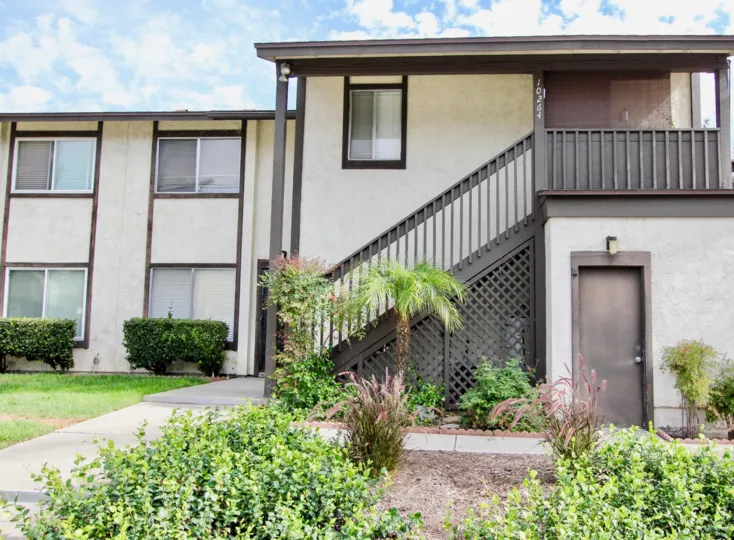 the front yard are wtih green landscaping in front of stairs leading to a second floor apartment in the Carefree East community in Santee, California