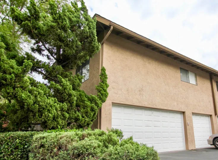 The Fletcher Valley Villas Community within Santee California is surrounded by lush foliage to contrast the building's natural colors in a multi-story home.