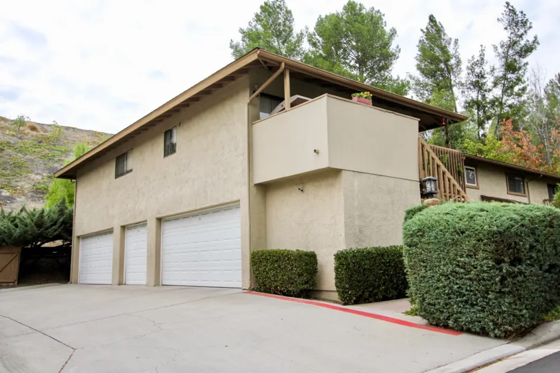 The exterior of Fletcher Valley Villas with three garage doors a balcony and paved driveway
