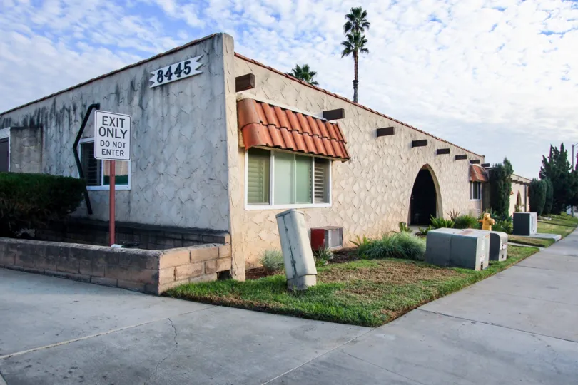 Building 8445, a stucco and tile building showing the exit driveway in community Horizon Village, Santee, CA