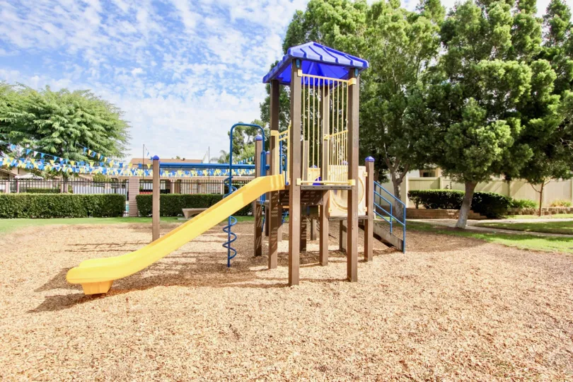 A yellow slide is attached to a playground set at a park at the Magnolia Meadows condos.