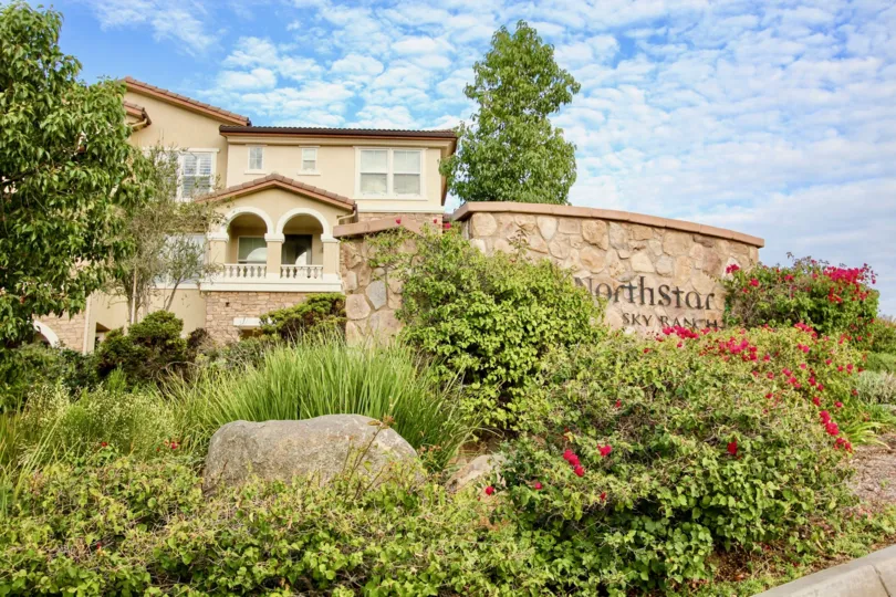 Northstar is just barely visible on the stone sign which sits in brush and a flower patch in forn of a row of an apartment building in Santee California