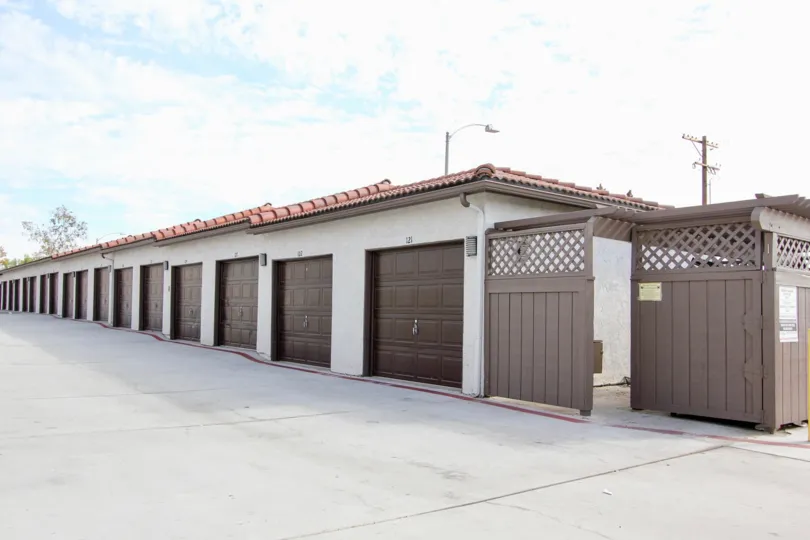 A row of brown garage doors sit on a building with a red tiled roof at the Riderwood Gardens condos