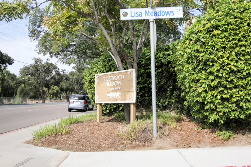 A stop sign sits on a pole near the Riverwood Meadows sign.