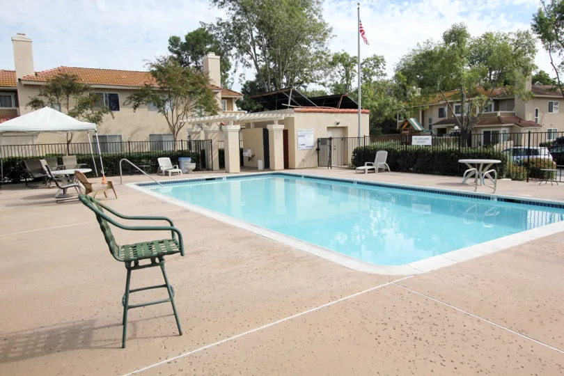 A sunny day poolside in the area of Riderwood Meadows, chair, pool, umbrella, trees