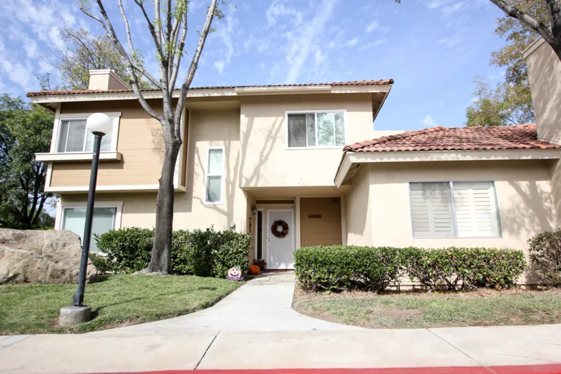 A two story single family home with a green lawn and rock landscaping in the Riderwood Meadows neighborhood in Santee, California