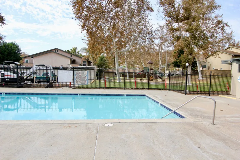 A sunny day poolside in the area of Riderwood Village, fence, cars, pool, trafficcones
