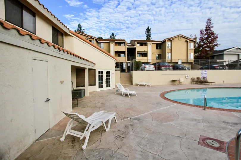A pool deck in Towne Villas with lawn chairs and parking area