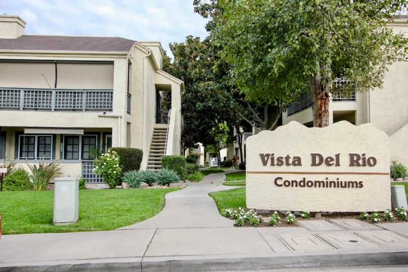 2-story condominium complex with green grass and trees