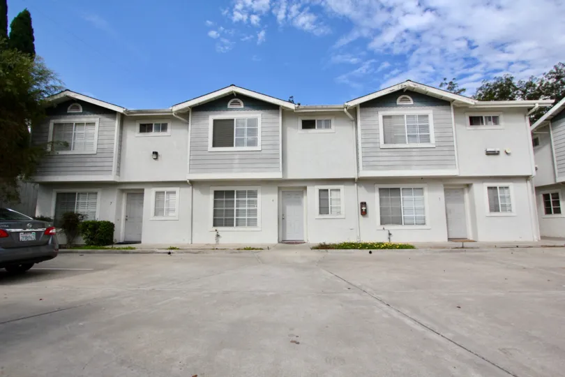 A paved parking lot leads to several white units in the Lamar Tonwhomes area.