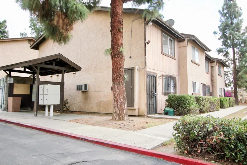 Corner of an apartment complex with paved sidewalks and green bushes in Parque Gillespie Spring Valley California