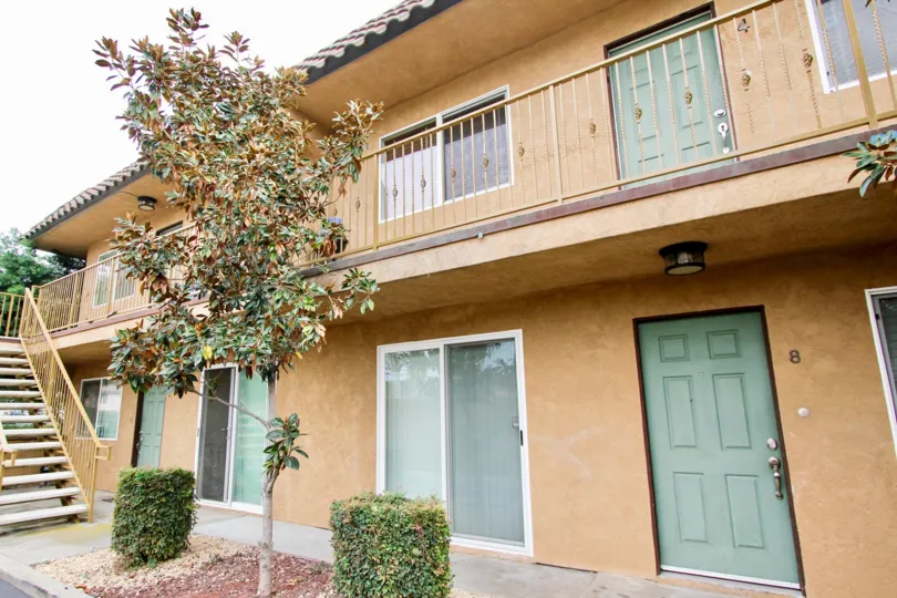Clear day at San Remos Villas with second floor balcony overlooking trees in driveway.