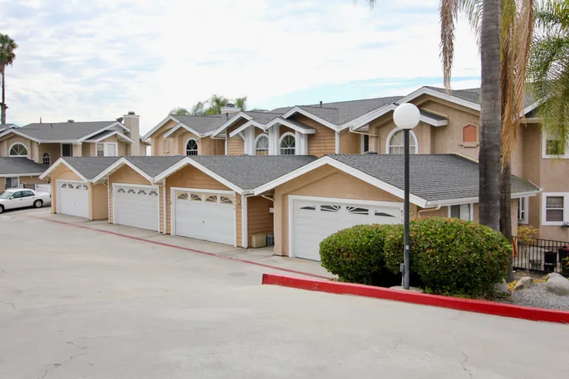 A car is parking in the street of Sunset Ridge and has trees, light lamp and bushes with many houses