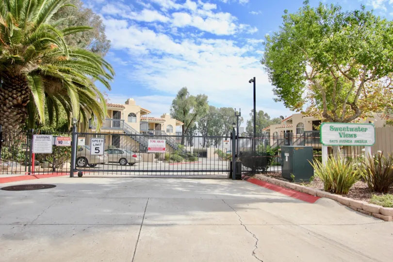 A sunny day in the area of Sweetwater Views, ouside, palm trees, gate, cars, parking lot