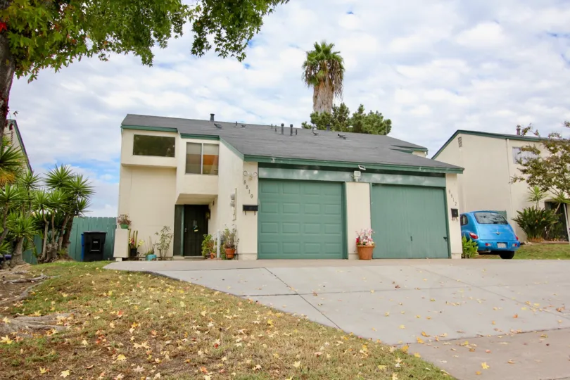 Duplex home with single car garage and pie shaped driveway with large sloping roof and front yard in Spring Valley