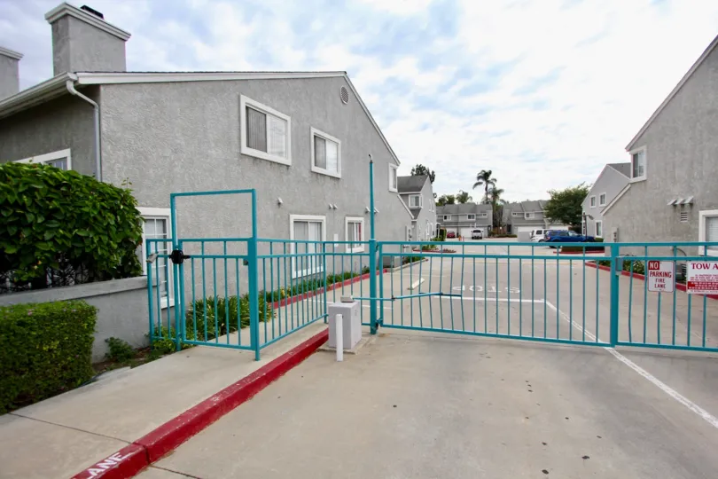 A sunny day in the area of Valencia Canyon, gate, fence, condo, cars, parking lot
