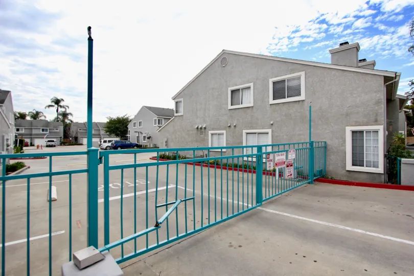 A teal colored metal gate secures the parking lot to the Valencia Canyon condos