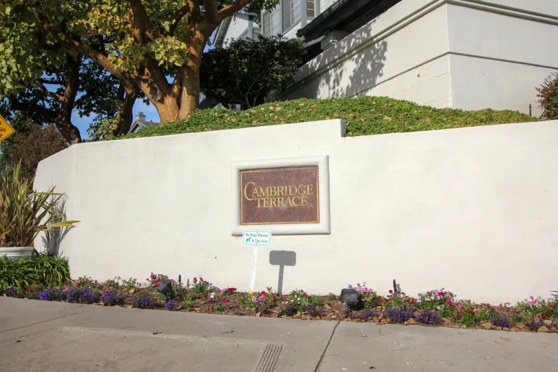 A marble sign with gold writing on a white wall at Cambridge Terrace in University City California