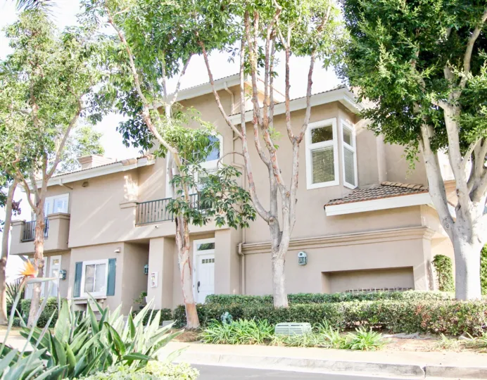 The front view of a few of the two-story townhomes with a row of trees in the Capri neighborhood.